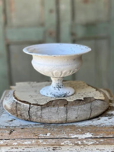 Cream colored round urn sitting on a wooden base