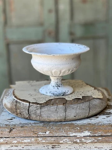 Cream colored round urn sitting on a wooden base